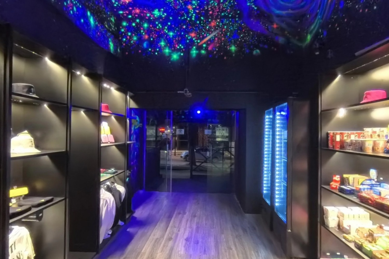 Corredor de vitrines iluminadas sob teto de galáxia em neon, capturado em 360°