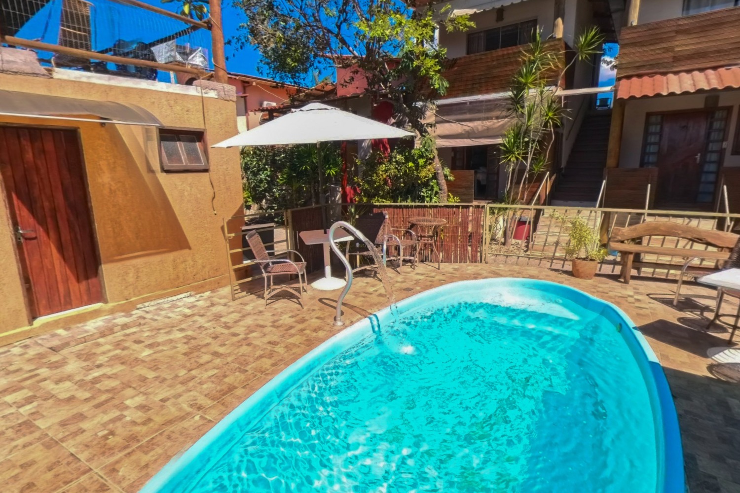 Piscina de pousada com deck, ombrelone e chalés, capturada em 360°